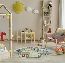 Hell gestaltetes Kinderzimmer mit rundem Spielteppich mit Straßenmotiv, Hausbett aus Holz, Kindersitzgruppe, Leiterregal und Sessel.