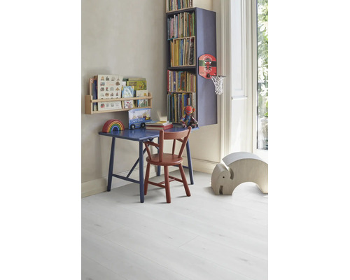 Helles, organisiertes Kinderzimmer mit blauem Holzschreibtisch, rotem Stuhl und Bücherregalen auf hellem Laminatboden in Holzoptik.