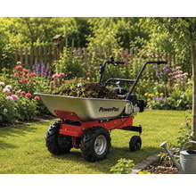 Motorisierte Schubkarre PowerPac mit Metallmulde, gefüllt mit Gartenabfällen, auf einer Rasenfläche in einem hellen, blühenden Garten.