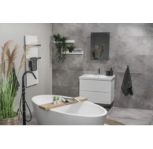 Modernes Badezimmer mit freistehender Badewanne, weißem Unterschrank und grauen Fliesen in Betonoptik.