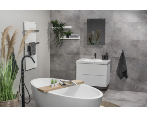 Modernes Badezimmer mit freistehender Badewanne, weißem Unterschrank und grauen Fliesen in Betonoptik.