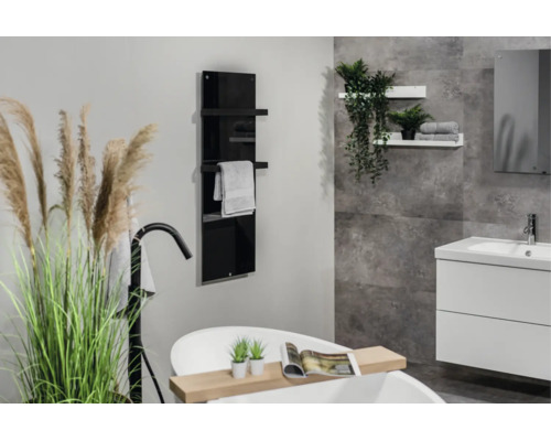 Modernes Badezimmer mit schwarzem Glas-Handtuchheizkörper, freistehender Badewanne und weißem Waschtisch vor grauer Wand in Steinoptik.