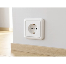 Schutzkontakt-Steckdose in Weiß, montiert an einer hellen Wand über einer Sockelleiste in Holzoptik.