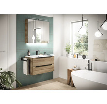 Helles Badezimmer mit Waschtischunterschrank in Eichenoptik, Waschbecken, schwarzer Armatur und dreitürigem Spiegelschrank mit Beleuchtung.