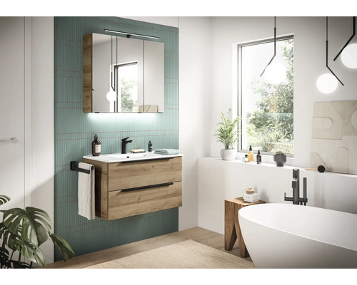 Helles Badezimmer mit Waschtischunterschrank in Eichenoptik, Waschbecken, schwarzer Armatur und dreitürigem Spiegelschrank mit Beleuchtung.