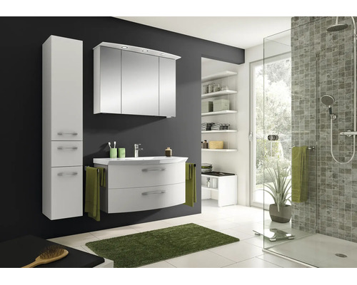 Modernes, helles Badezimmer mit weißem Waschtisch, Spiegelschrank mit Beleuchtung, Hochschrank und Glasdusche vor einer dunkelgrauen Wand.