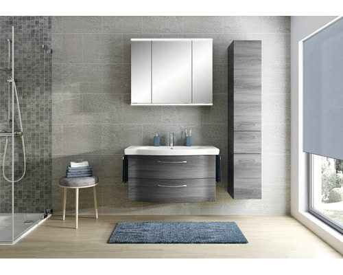 Modernes Badezimmer mit Waschtischunterschrank in Holzoptik, weißem Waschbecken, Spiegelschrank mit Beleuchtung und passendem Hochschrank.