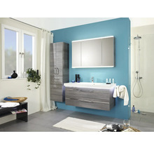 Modernes Badezimmer mit grauem Waschtischunterschrank, dreitürigem Spiegelschrank, Hochschrank und begehbarer Dusche vor blauer Wand.