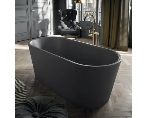 Freistehende ovale Badewanne in Dunkelgrau in einem modernen Raum mit Parkettboden, goldfarbener Standarmatur und einem dunklen Sessel.