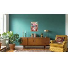 Modernes Wohnzimmer mit Holz-Sideboard, Samtsessel, großer Monstera-Pflanze und gerahmtem Bild eines Leoparden im Anzug.