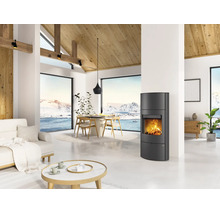 Moderner Kaminofen in einem hellen Wohnzimmer mit hohen Decken, Holzgebälk und Panoramafenstern mit Blick auf eine Schneelandschaft.