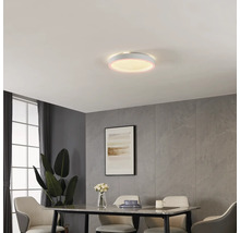 Runde LED-Deckenleuchte in modernem Esszimmer mit Wandpaneelen in Steinoptik, Esstisch und Polsterstühlen. Die Leuchte hat einen leuchtenden Rand.