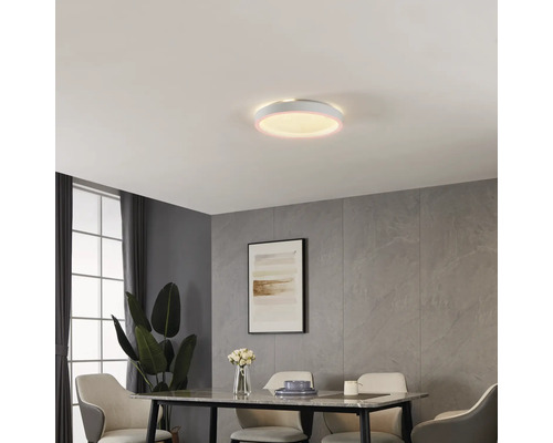 Runde LED-Deckenleuchte in modernem Esszimmer mit Wandpaneelen in Steinoptik, Esstisch und Polsterstühlen. Die Leuchte hat einen leuchtenden Rand.