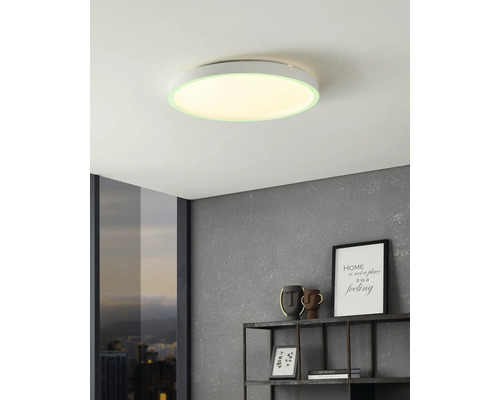Flache runde LED-Deckenleuchte in einem modernen Wohnraum mit strukturierter grauer Wand, Wandregal und Fenster mit Blick auf die Stadt.