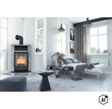 Moderner, heller Raum mit einem Kaminofen mit Natursteinverkleidung und brennendem Feuer, dazu ein Bett und ein geometrischer Beistelltisch. (Image AI modified or generated)