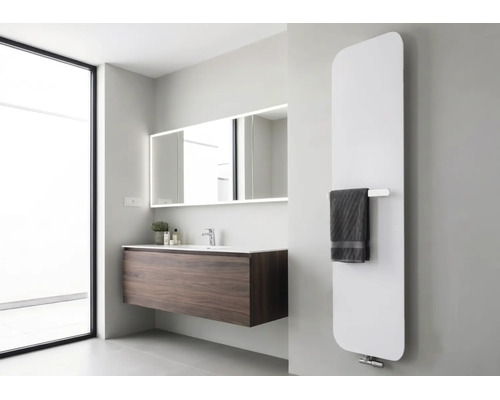 Moderner vertikaler Design-Heizkörper in einem hellen Badezimmer mit dunklem Waschtisch und beleuchtetem Spiegel.