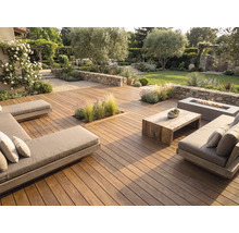 Großzügige Holzterrasse mit modernen Loungemöbeln, einem Holztisch, einer Feuerstelle und Natursteinmauern in einem gepflegten Garten.