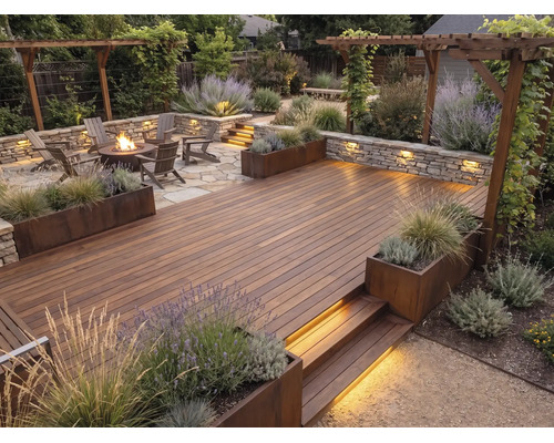 Moderne Gartengestaltung mit Holzterrasse, Steinmauer mit Beleuchtung, Feuerstelle, Adirondack-Stühlen, Pergola und bepflanzten Beeten.