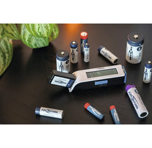 Ansmann Batterietester mit Digitalanzeige und verschiedenen Ansmann Batterien auf einem Tisch.