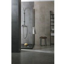 Modernes Badezimmer mit ebenerdiger Dusche, Glastrennwand, verchromten Duscharmaturen, Wandfliesen in Steinoptik und einem Hocker.