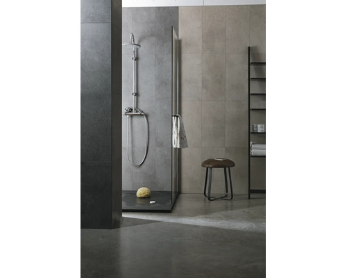 Modernes Badezimmer mit ebenerdiger Dusche, Glastrennwand, verchromten Duscharmaturen, Wandfliesen in Steinoptik und einem Hocker.