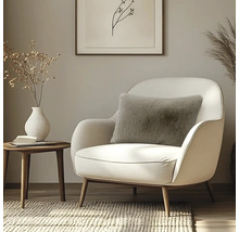 Flauschiges Dekokissen in Hellbraun auf einem eleganten, weißen Sessel im modernen Wohnzimmer mit Holz-Beistelltisch.