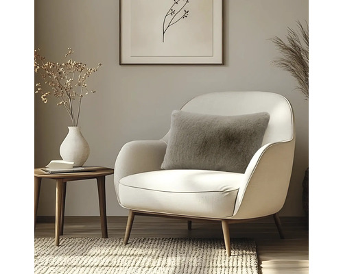 Flauschiges Dekokissen in Hellbraun auf einem eleganten, weißen Sessel im modernen Wohnzimmer mit Holz-Beistelltisch.