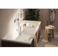 Moderne Badewanne mit Wannenablage aus Metall in einem elegant eingerichteten Badezimmer mit Duscharmatur und Holzschemel als Ablagefläche