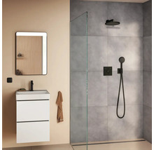 Modernes Badezimmer mit weißem Waschbeckenunterschrank, beleuchtetem Wandspiegel und einer offenen Walk-in Dusche mit grauen Fliesen.