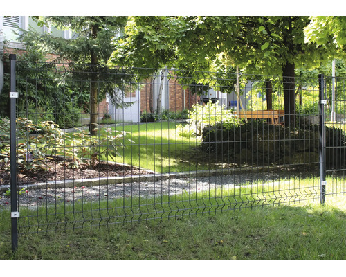 Stabmattenzaun aus Metall in einem Garten mit Pfosten und Befestigungselementen vor einer Grünfläche mit Bäumen und Hauswand