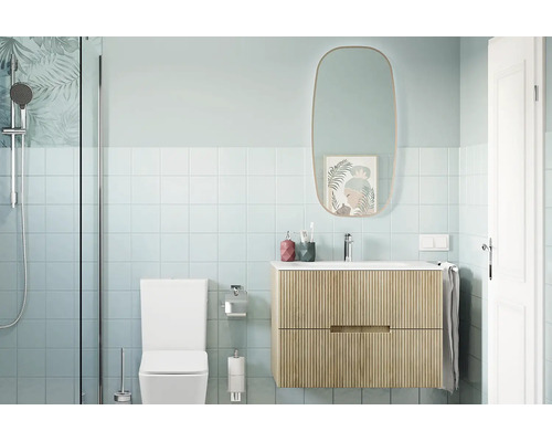 Modernes Badezimmer mit einem hängenden Waschtisch mit Rillenstruktur, einem ovalen Spiegel, einer Toilette und einer Dusche mit Glaswand.