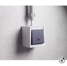 Aufputz Lichtschalter mit Kontrollleuchte montiert auf einer Wand mit Kabelkanal (Image AI modified or generated)