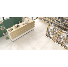 Innenraumansicht mit großformatigen hellen Bodenfliesen in einem modern eingerichteten Raum mit Holztheke und Bücherregalen.