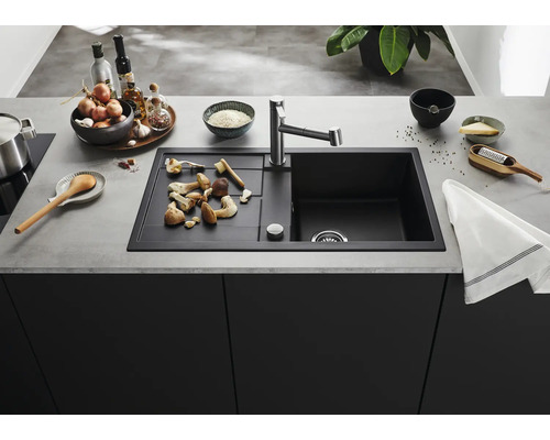 Moderne Küchenspüle mit Abtropffläche und Armatur in einer organisierten Küche mit Kochutensilien und Lebensmitteln auf der Arbeitsplatte.
