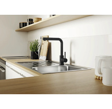 Moderne Küchenspüle aus Edelstahl mit schwarzer Einhebel Küchenarmatur auf einer Arbeitsplatte in Holzoptik in einer hellen Küche.