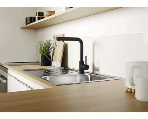 Moderne Küchenspüle aus Edelstahl mit schwarzer Einhebel Küchenarmatur auf einer Arbeitsplatte in Holzoptik in einer hellen Küche.
