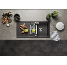 Moderne Küchenspüle aus Verbundwerkstoff mit Abtropffläche, Edelstahlbecken und Armatur in einer organisierten Küche mit Lebensmitteln von oben.