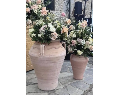 Zwei große Terrakotta Amphoren mit Blumenarrangement auf einem Steinboden.