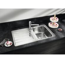Edelstahl Einbauspüle mit Abtropffläche und moderner Küchenarmatur eingebaut in einer dunklen Arbeitsplatte mit Küchenaccessoires.