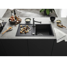 Moderne Küchenspüle mit Abtropffläche und Armatur in einer organisierten Küche mit Kochutensilien und Lebensmitteln auf der Arbeitsplatte.