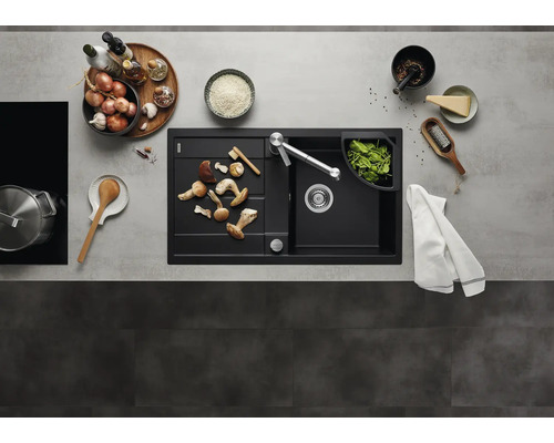 Moderne schwarze Einbauspüle mit Abtropffläche und Küchenarmatur in einer organisierten Küche mit Kochutensilien und frischen Lebensmitteln.