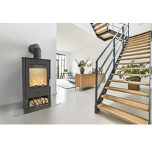 Moderner Kaminofen mit brennendem Feuer und integriertem Holzlager in einem hellen, offenen Wohnbereich mit einer Holztreppe.