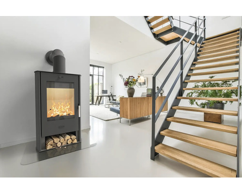 Moderner Kaminofen mit brennendem Feuer und integriertem Holzlager in einem hellen, offenen Wohnbereich mit einer Holztreppe.