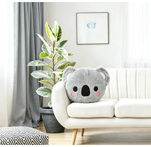 Plüschkissen in Koalaform auf einem weißen Sofa in einem hellen, wohnlich eingerichteten Zimmer.