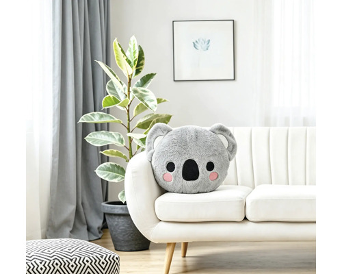 Plüschkissen in Koalaform auf einem weißen Sofa in einem hellen, wohnlich eingerichteten Zimmer.