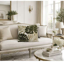 Dekokissen mit Blattmotiv auf einem klassischen Sofa in einem hellen, elegant eingerichteten Wohnzimmer.