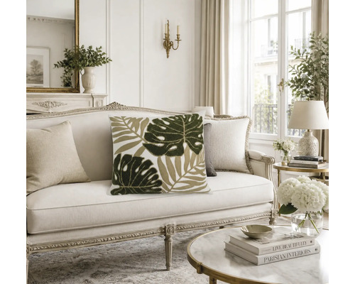 Dekokissen mit Blattmotiv auf einem klassischen Sofa in einem hellen, elegant eingerichteten Wohnzimmer.