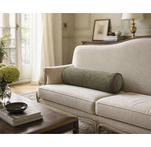 Stoffrolle als Dekokissen auf einem hellen Sofa in einem hellen Wohnzimmer mit Couchtisch und Blumen.