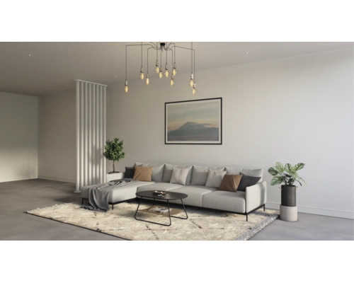 Modernes Wohnzimmer mit Ecksofa, Couchtisch und Pendelleuchte. Der Raum ist hell und minimalistisch eingerichtet mit einem Teppich und Pflanzen.