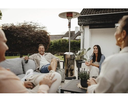 Gruppe von Freunden sitzt abends auf einer Terrasse mit einem Terrassenheizstrahler für behagliche Wärme.